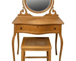 775 - Antique Vanity w/ Bench 55"x33"x20" (Description): Antique vanity with bench. The vanity  features a decorative carved frame with an  oval tilting mirror, serpentine front drawer  with knob pull and keyhole, and graceful  cabriole legs. The accompanying bench has a caned seat. Measures 55 inches high 33 inches  wide  20 inches deep.
