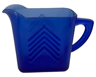334 - Blue Glass Pitcher 4"x6"x2.5" (Description): Blue glass pitcher featuring an Art  Deco-inspired chevron pattern on the body.  The pitcher has a distinctive angular shape  with a shaped pouring spout and applied  handle. Measures 4 inches by 6 inches by 2.5 inches.