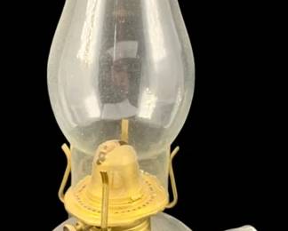 413 - Oil Lamp 11" (Description): Oil lamp measuring 11 inches in height.  Features a clear glass base with handle and  glass chimney with brass fittings.