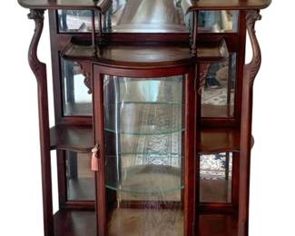 61 - Antique Mahogany Curio Cabinet 65"x34"x14" (Description): Antique mahogany curio cabinet featuring  elegant curved glass panels, mirrored back,  and glass display shelves. The cabinet  showcases ornate carved details, turned  spindle supports, and decorative upper shelving with a shaped mirror crest. Stands  on graceful cabriole legs with a locking  door. Measures 65 inches tall by 34 inches  wide by 14 inches deep.