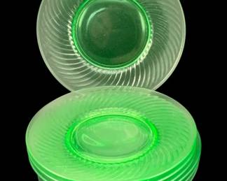 410 - 8 Uranium Green Glass Plates 10" (Description): Eight uranium glass plates featuring a swirl  pattern design. Each plate measures 10 inches  in diameter. The characteristic green  uranium glass will fluoresce under UV light.