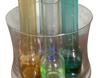 42 - Centerpiece with 7 Bud Vases (Description): Seven-piece set featuring colored glasses  with an accompanying ice bowl. The bowl  measures 6.5 inches in diameter, and the  glasses stand 6 inches tall.