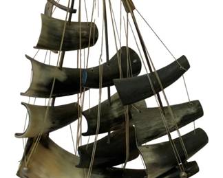 86 - Bone Model Ship 13"x11"x4" (Description): A decorative model ship crafted from bone.  The piece features multiple carved bone sails  arranged on masts with string rigging, all  mounted on a curved bone base. Measures 13  inches by 11 inches by 4 inches.