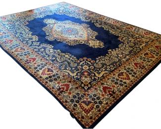 665 - Large Rug 9'10"x13'11" (Description): Large rug measuring 9'10" x 13'11". Features  a traditional Persian-style design with a  central medallion on a deep blue field,  surrounded by ornate floral and foliate  patterns in gold, red, and cream tones. Multiple decorative borders frame the piece.