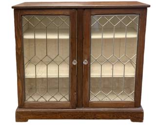 518 - Antique Cabinet 37"x38"x10.75" (Description): Antique cabinet featuring two glass-paneled  doors with decorative leaded glass design in  a diamond pattern. The cabinet includes  interior shelving and glass knob hardware.  Measures 37 inches wide by 38 inches tall by 10.75 inches deep.