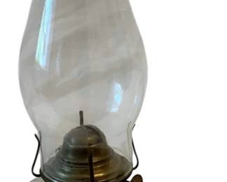 633 - Oil Lamp 11.5" (Description): Oil lamp measuring 11.5 inches in height.  Features a clear glass chimney, brass burner  mechanism with wick adjustment, and a pressed  glass base with finger loop handle.