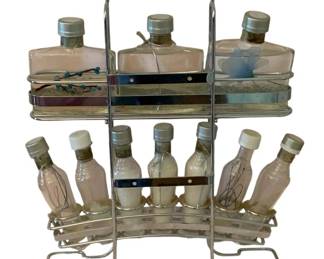112 - Metal Rack w/ Glass Bottles 18"x15"x4" (Description): Metal rack with glass bottles. The two-tiered  chrome rack holds multiple decorative glass  bottles of varying sizes. Measures 18 inches  by 15 inches by 4 inches.