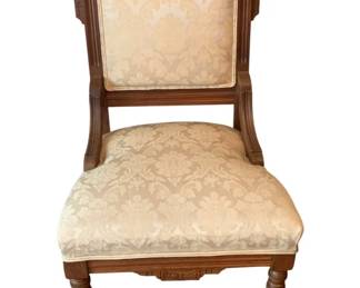 60 - Antique Chair 37"x21"x28" (Description): Antique chair featuring carved wooden frame  with decorative crest rail, upholstered seat  and back in cream damask fabric, and turned  front legs with casters. Measures 37 inches  high by 21 inches wide by 20 inches deep.