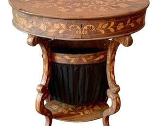 54 - Inlaid Wood Sewing Stand w/ contents (Description): Inlaid wood sewing stand featuring intricate  marquetry work with floral and foliate  designs throughout. The oval top lifts to  reveal storage, while the base includes a  fabric-lined sewing basket suspended between elegantly curved legs with a decorative  stretcher. Measures 29 inches high by 24  inches wide by 17 inches deep.