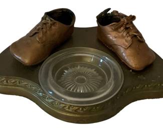 90 - Bronze Baby Shoes Ashtray 3.5"x9"x6.5" (Description): Bronze baby shoes ashtray featuring a  decorative base with glass insert. Measures 3  1/2" x 9" x 6.5".