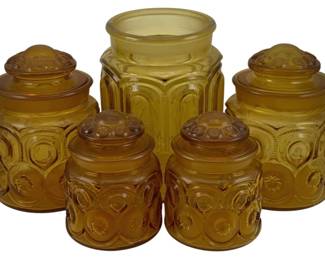 472 - 5 Amber Glass Canister Set - missing one lid (Description): A five-piece amber glass canister set. One  canister is missing its lid. The set features  decorative pressed glass canisters in  varying sizes, ideal for kitchen storage or  display.
