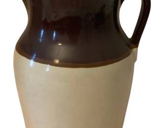 215 - Roseville Pitcher 11.5"x9"x8" (Description): Roseville pitcher featuring a two-tone design  with a dark brown glazed upper portion and  cream-colored lower body. Measures 11.5  inches by 9 inches by 8 inches.