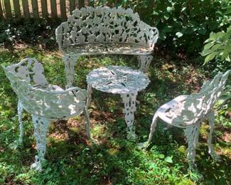 12 - 4 Cast Iron Outdoor Set Table Chairs Bench (Description): Four-piece cast iron outdoor furniture set  featuring ornate openwork design. The set  includes a bench, chairs, and table.  Measurements: table 15 x 20 inches; chairs 25  x 22 x 15 inches; bench 28 x 38 x 19 inches.