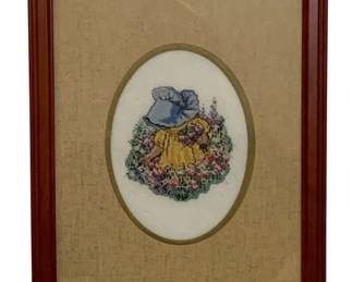 737 - Framed Needlepoint 11"x9.25" (Description): A framed needlepoint depicting a figure in a  yellow dress and blue bonnet surrounded by  flowers. The needlework is set within an oval  mat and housed in a wooden frame. Measures  11 inches by 9.25 inches.