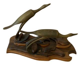 111 - Carved Wood Birds Sculpture 10"x16"x9" (Description): A carved wood sculpture depicting birds in  flight. The piece features detailed carving  work showing waterfowl in dynamic poses,  mounted on a sculpted wooden base with  organic flowing forms. Measures 10 inches by 16 inches by 9 inches.