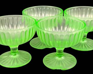 377 - 4 Uranium Green Glass Footed Sherbets (Description): A set of four uranium glass footed dessert  dishes featuring a ribbed design. The set is  sold as-is with noted chips. Each dish  measures 3.25 inches by 3.5 inches.