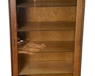 41 - Antique Oak Bookcase w/ Single Door 65.5"x30"x13" (Description): Antique bookcase cabinet featuring a glass  front door with decorative rope twist trim,  multiple interior shelves, and a shaped apron  base with bracket feet. The cabinet has a  raised back gallery with carved molding detail. Measures 65.5 inches highby 30 inches  wide by 13 inches deep.