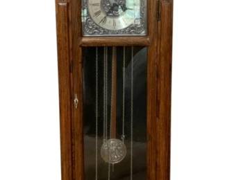 673 - Antique Grandfather Clock 78"x21"x13" (Description): Antique grandfather clock featuring a classic  tall case design with decorative bonnet top  and urn finial. The clock displays a silvered  dial with Roman numerals and ornate  spandrels. A glass door reveals the pendulum and chain weights. Measures 78 inches tall by  21 inches wide by 13 inches deep. Used as is electric/electronic/mechanical  item. No guarantee all components, untested.