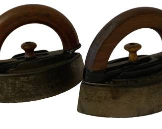 181 - 2 Antique Irons (Description): A pair of antique irons featuring wooden  handles and metal construction. These two  vintage flat irons represent traditional  laundry implements from an earlier era.