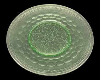 530 - Uranium Green Glass Plate 9.5" (Description): Uranium glass plate measuring 9.5 inches in  diameter. The plate features a pressed glass  construction with a distinctive honeycomb or  thumbprint pattern and a central sunflower  motif. The glass exhibits the characteristic pale green coloration typical of uranium  glass.