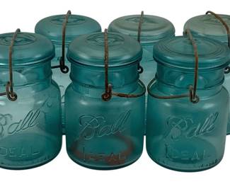 505 - 6 Ball Mason Jars 6" tall (Description): A lot of six Ball Ideal mason jars in the  classic blue-green glass. Each jar features  the embossed Ball script logo and "IDEAL"  lettering, with glass lids and wire bail  closures. Each jar measures 6 inches tall.
