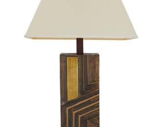 132 A Brutalist style table lamp Mid/late 20th century Unmarked Patinated and polished bronze with enameled accents, on a wood base, issuing a single light with fabric shade, electrified Height without harp 25 1/2 in., width 8 in., depth 4 5/8 in.; shade height 11 in., width 19 1/4 in., depth 12 1/2 in. Estimate: $200 - $400