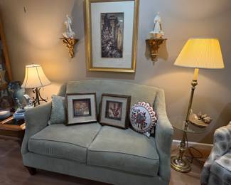 Pretty loveseat holding nice framed art in the living room.