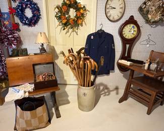 A collection of canes standing in a nice crock. Two old antique school desks.
