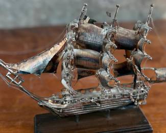 This lot features a sterling silver ship sculpture that sits on a wood plinth. The silver weight alone is 223.89 grams. This piece measures (with plinth), 8” H x 12” W x 3” D.