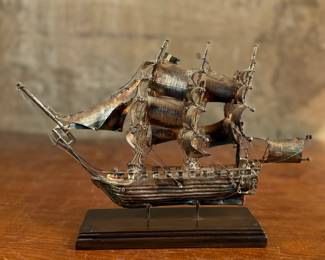 This lot features a sterling silver ship sculpture that sits on a wood plinth. The silver weight alone is 223.89 grams. This piece measures (with plinth), 8” H x 12” W x 3” D.