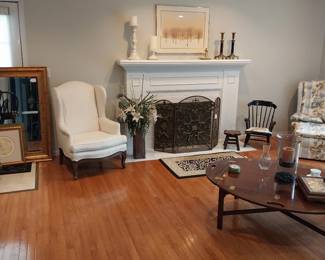 wall mirrors, cream wing back chair, floral wing back chair and ottoman, child’s rocker, fireplace screen, coffee table, candle holders