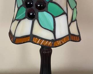 Tiffany-style accent lamp features a green floral stained glass shade on a dark metal base