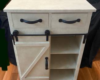 farmhouse-style distressed white wood storage cabinet featuring a black metal sliding barn door and two top drawers