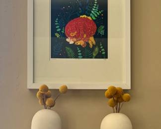 Framed folk art print of a curled fox/animal amid ferns, pair of sculptural face-form ceramic vases (mustache and lips design) with dried billy ball floral stems.