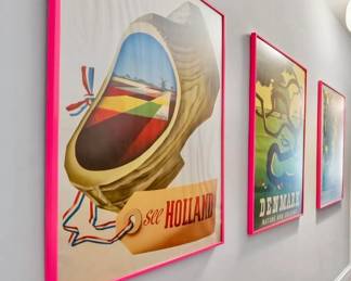 Set of vintage-style travel posters including “See Holland” and “Denmark,” matted in red frames.