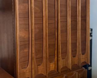 Tall walnut Brutalist-style wardrobe/armoire with sculpted arched panel doors, matching design to the credenza — mid-century case piece with molded geometric door fronts.