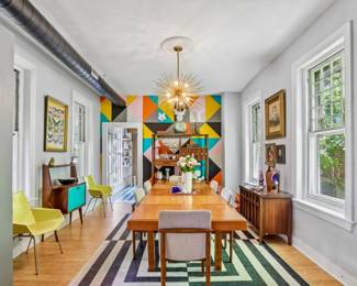 Long walnut dining table with upholstered chairs, pair of yellow mid-century molded shell chairs, teak sideboard/credenza, brass sputnik chandelier, geometric black-and-white striped rug, gallery wall of framed art, vintage portrait prints.
