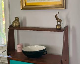 Mid-century walnut secretary desk with turquoise laminate front and splayed legs, framed antique butterfly specimen print, brass elephant and owl figurines, black and white ceramic bowl.