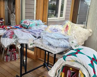 Over 20 handmade quilts. Sewing table underneath the quilts