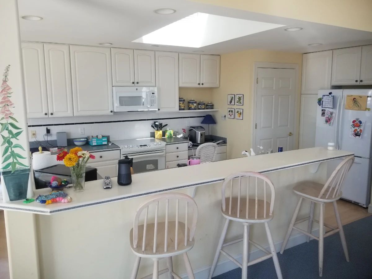 Crisp white galley kitchen with island. 3 bar stools available