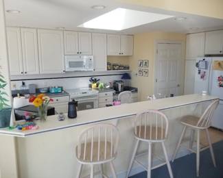 Crisp white galley kitchen with island. 3 bar stools available
