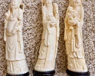Set of three vintage Asian-style figurines representing the traditional gods of Prosperity, Longevity, and Happiness. Ivory-colored resin or carved composite on wooden display bases. Beautiful display pieces for Asian-inspired décor or collectors.