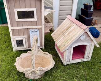 Whimsical outdoor décor including a decorative cat house, small dog house, and concrete garden basket planter.