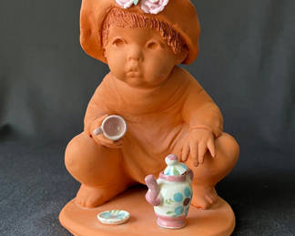 Lot 82: Terracotta baby with miniature tea set and white winged angel figurine