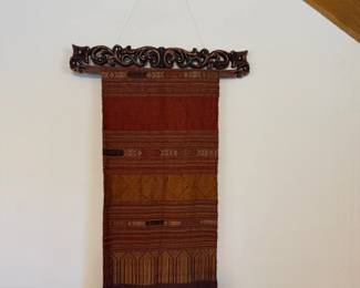 Handwoven Thai silk in deep reds, ochre, and gold with a fringed hem, suspended from a carved Indonesian hardwood frame. $40