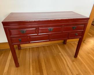 Vintage cinnabar-red lacquer console on tall square legs. Three top drawers with brass butterfly escutcheons over two flanking drawers. Warm patina from honest age. $150