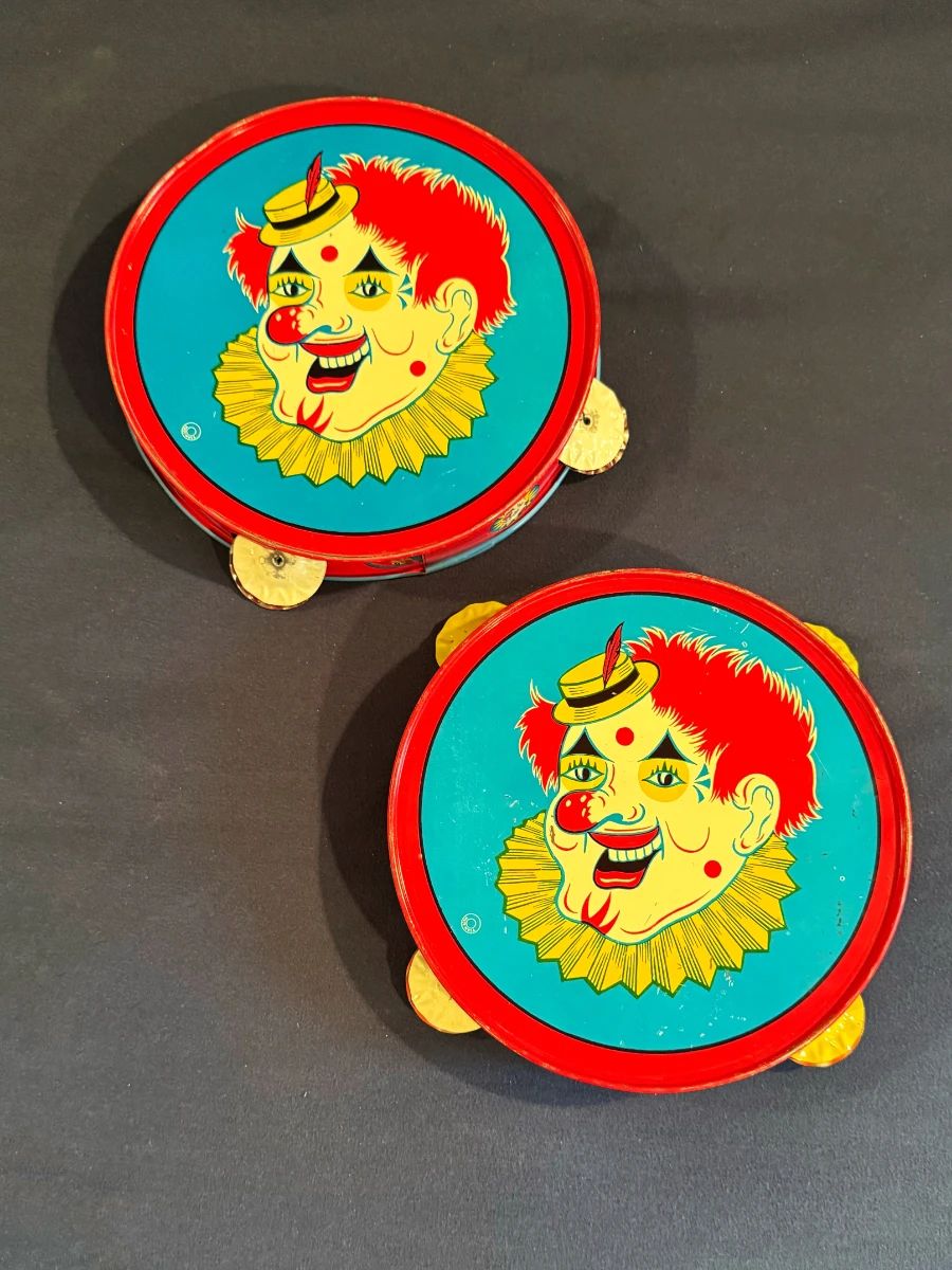 These are vintage mid-20th-century tin litho clown tambourines/noisemakers, produced by The U.S. Metal Toy Manufacturing Co.
