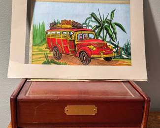 Here we have a framed watercolor and ink artwork featuring a vintage red woody station wagon filled with luggage, created by Alabama artist Elsie Prather. Beneath it is a wooden storage chest that features a rich dark wood finish, a hinged top compartment, and two small pull drawers with brass-tone knobs.