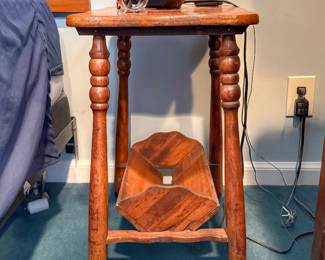 This vintage wooden side table features heavily turned spool legs and a built-in lower trough magazine rack.