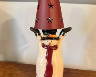 This is a vintage Russ ceramic snowman tealight candleholder featuring a crackle-glaze finish, a burgundy scarf, and a star-punched metal shade held up like a hat.